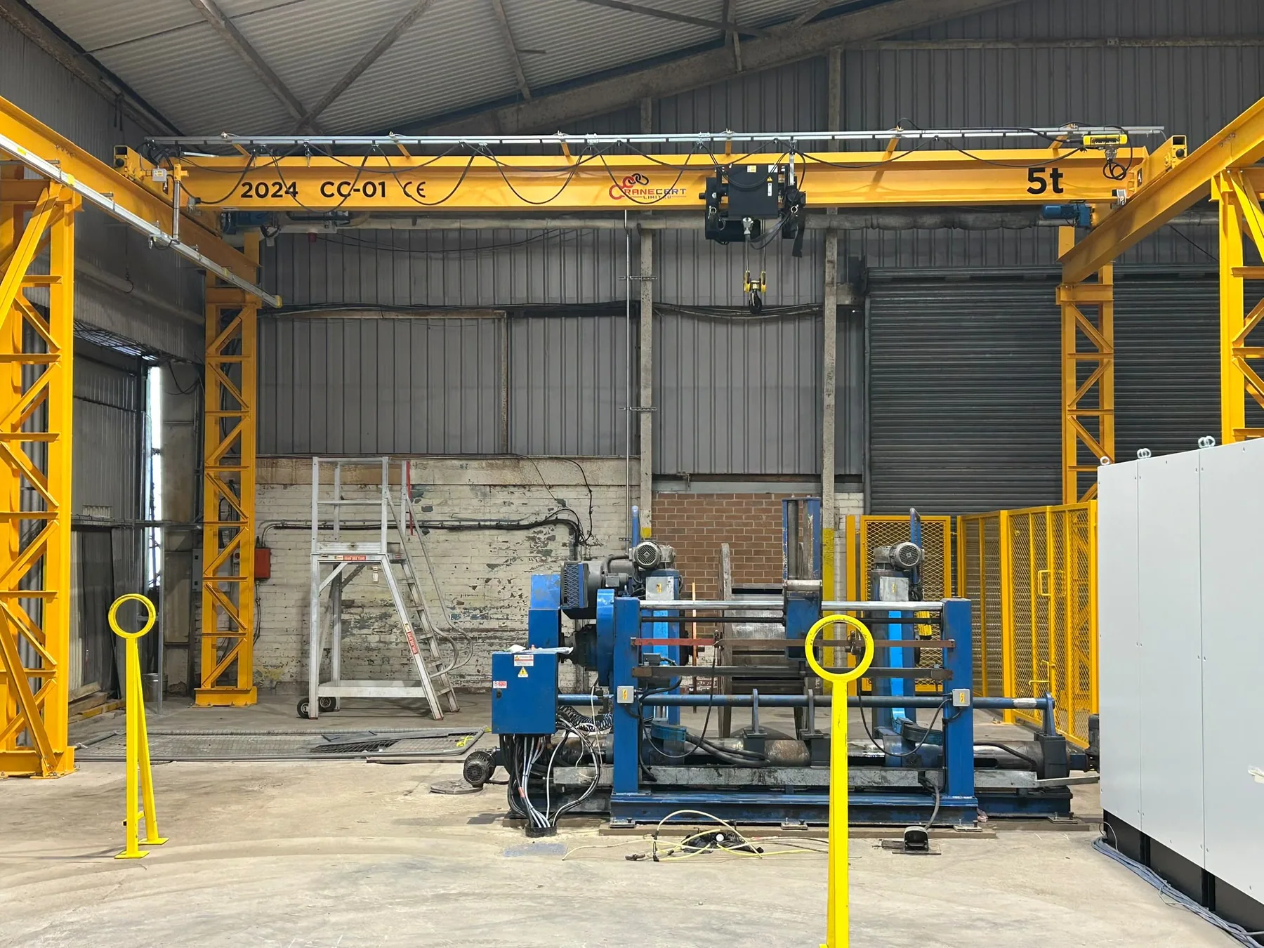 Freestanding yellow gantry crane installed around industrial equipment